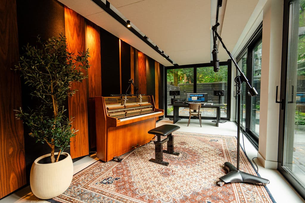 The recording room on the Admiralengracht: an upright piano, a microphone on a boom, monitors, glass onto the garden