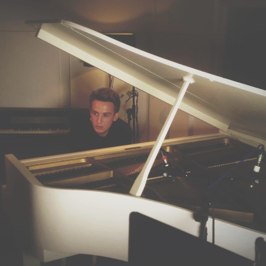 A teenage Ivo Adelaar behind a grand piano with recording microphones set inside the open lid