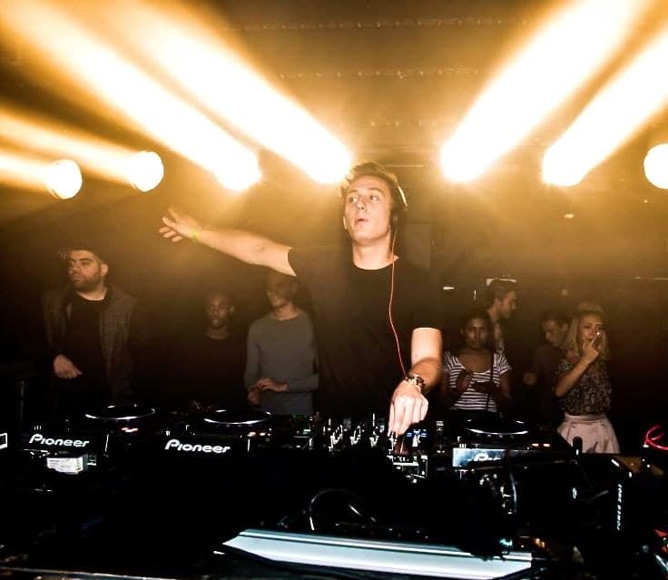 Ivo Adelaar playing to a crowd at Club AIR in Amsterdam, arm out under the stage lights