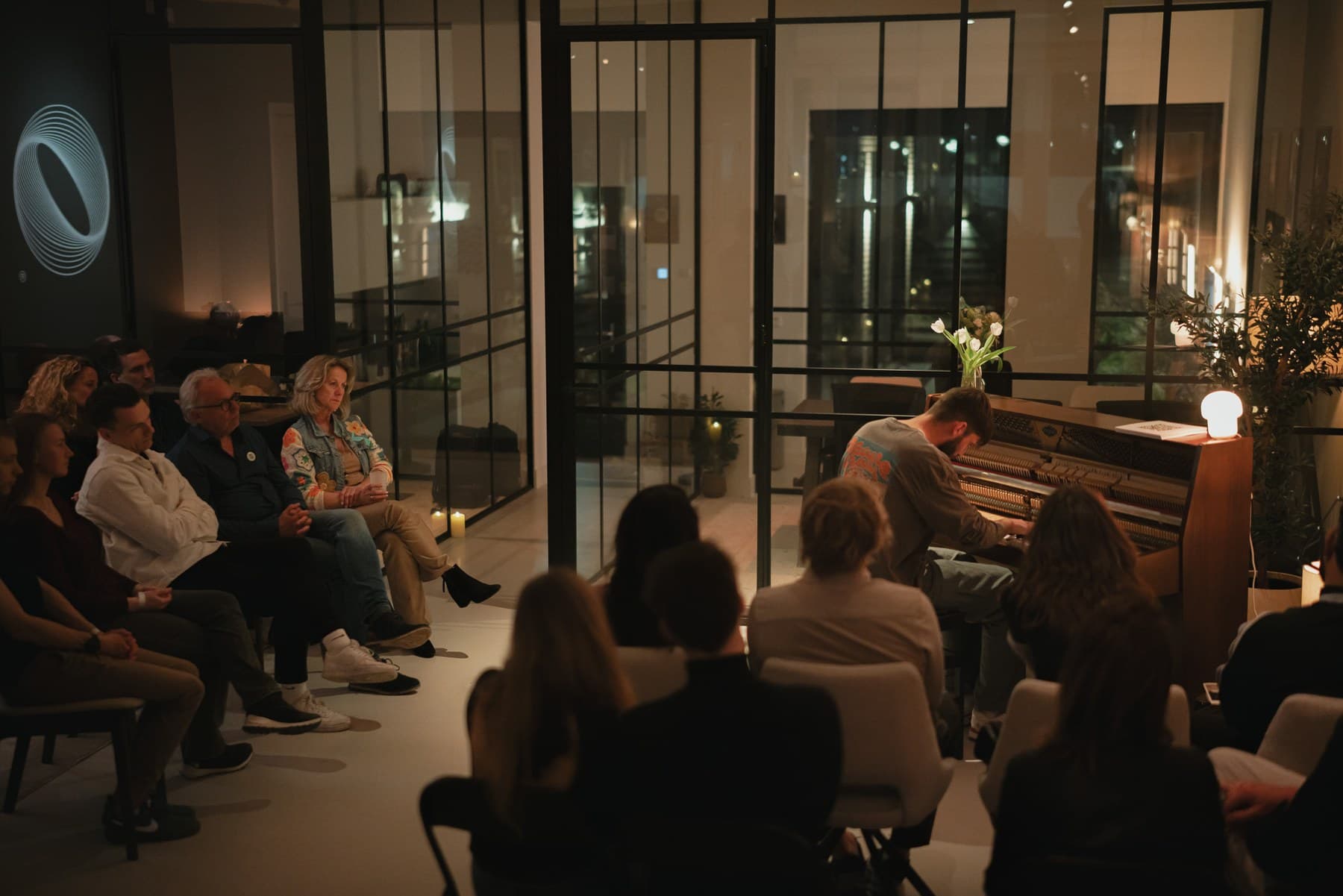 A Piano Day session in the office piano room: a pianist at the opened upright, the audience seated close, candles and the Disruptive Records mark on the wall